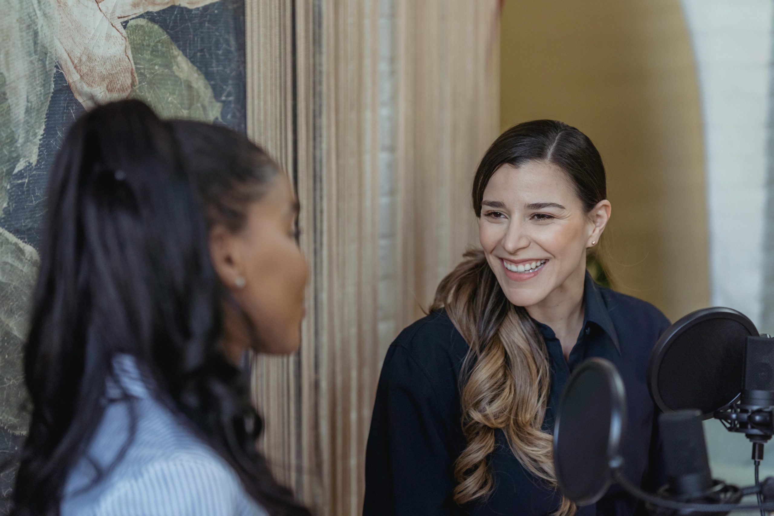 A candid moment of two women chatting during a podcast recording session.